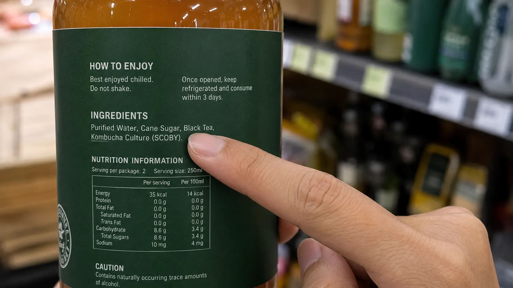 Reading kombucha ingredient list in Singapore supermarket — checking for natural flavoring